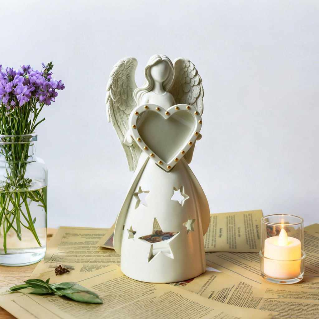 White angel figurine with a heart, placed on a table with a candle and flowers.