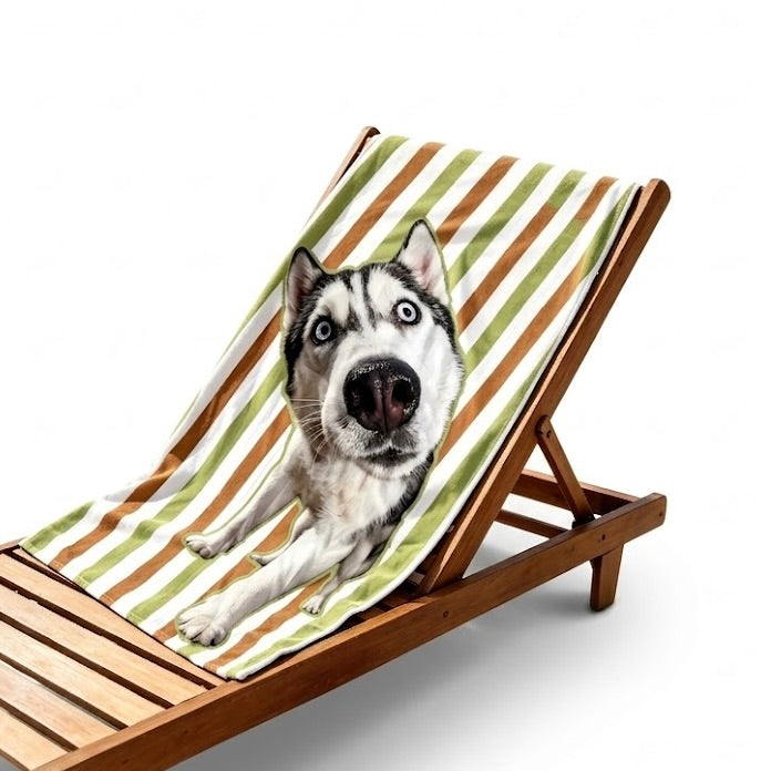A cool Siberian Husky with sunglasses relaxes on a personalized custom pet portrait beach towel with striped patterns and a unique personalization, set on a beach