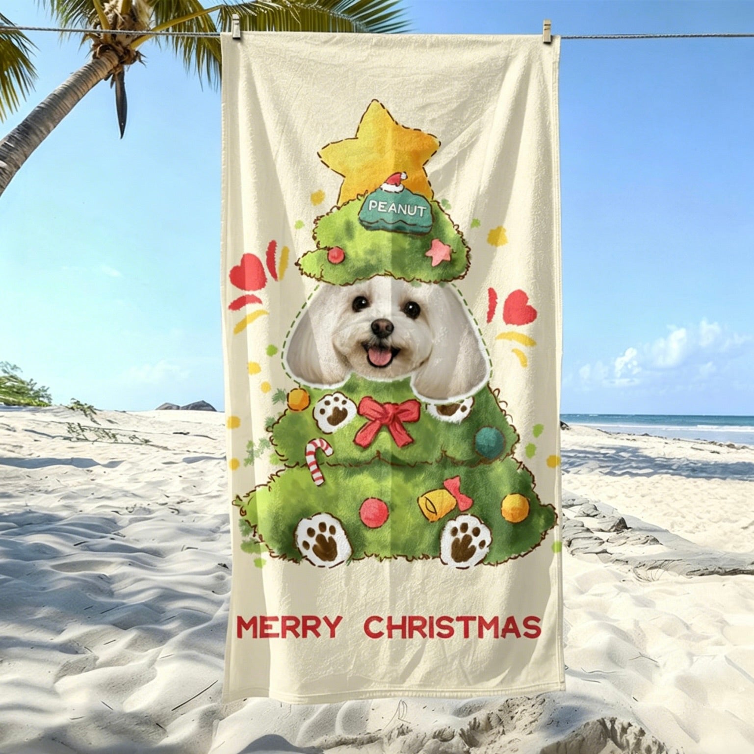 A festive custom pet portrait beach towel featuring a cute white dog named Peanut styled as a Christmas tree, hanging on a sunny beach.