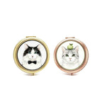 Two compact mirrors with cat illustrations on a white background