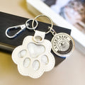 Keychain with paw-shaped holder and circular tag on a blurred background