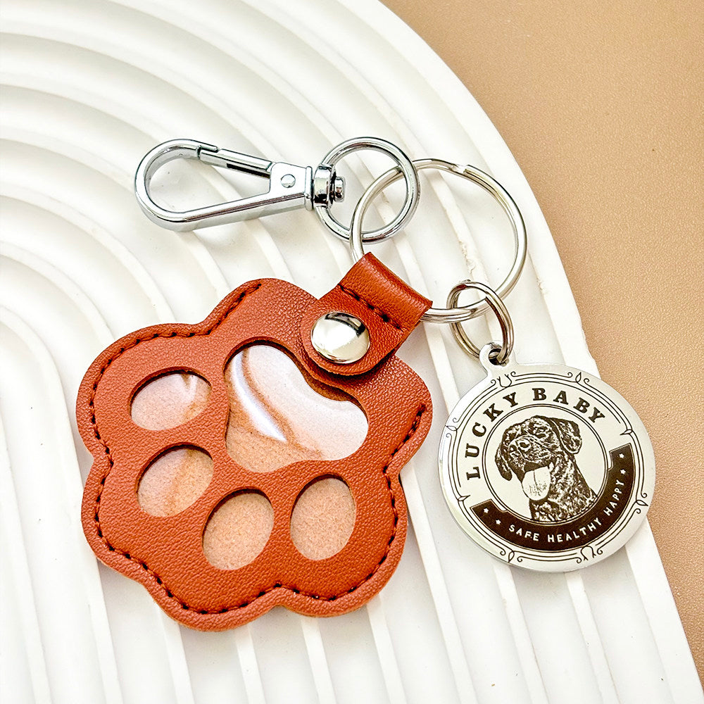 Brown leather paw-shaped keychain with a silver 'Lucky Baby' charm on a white background