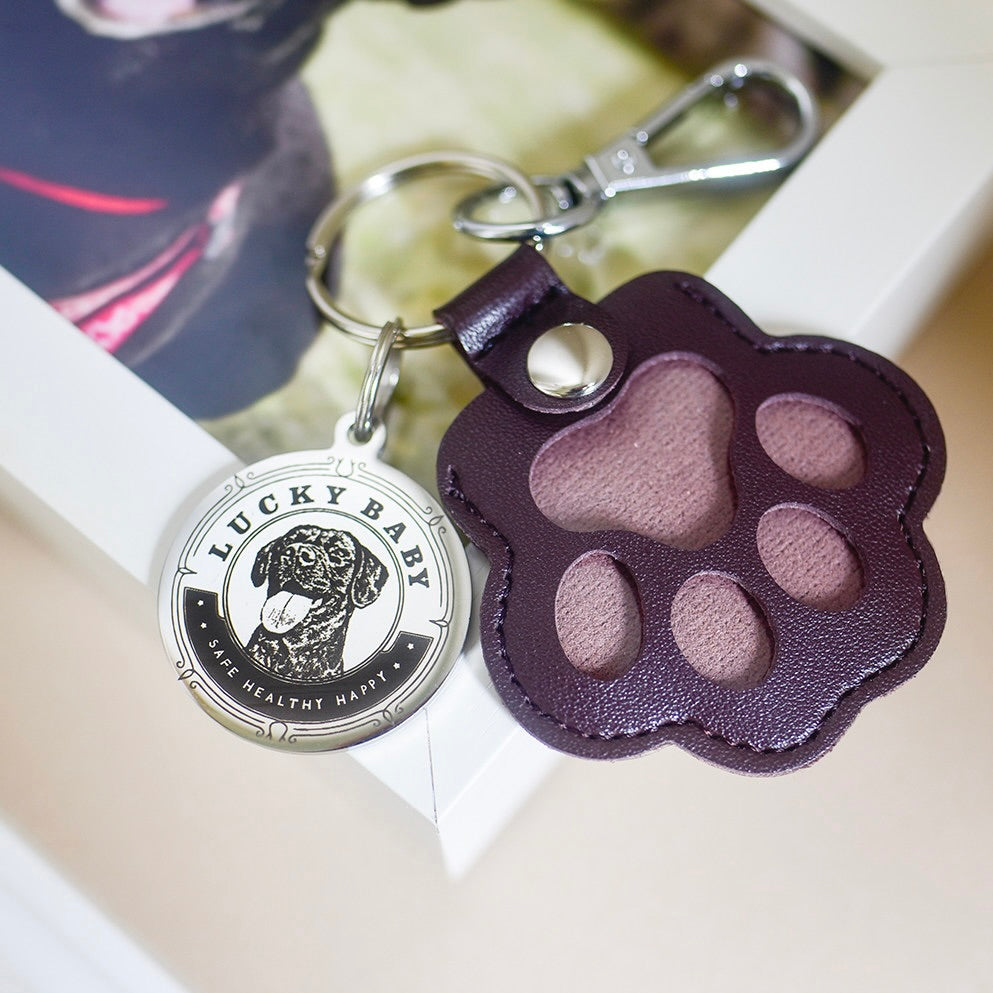 Keychain with paw-shaped leather tag and 'Lucky Baby' charm on a white surface