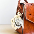 Brown leather bag with a 'Lucky Baby' keychain attached
