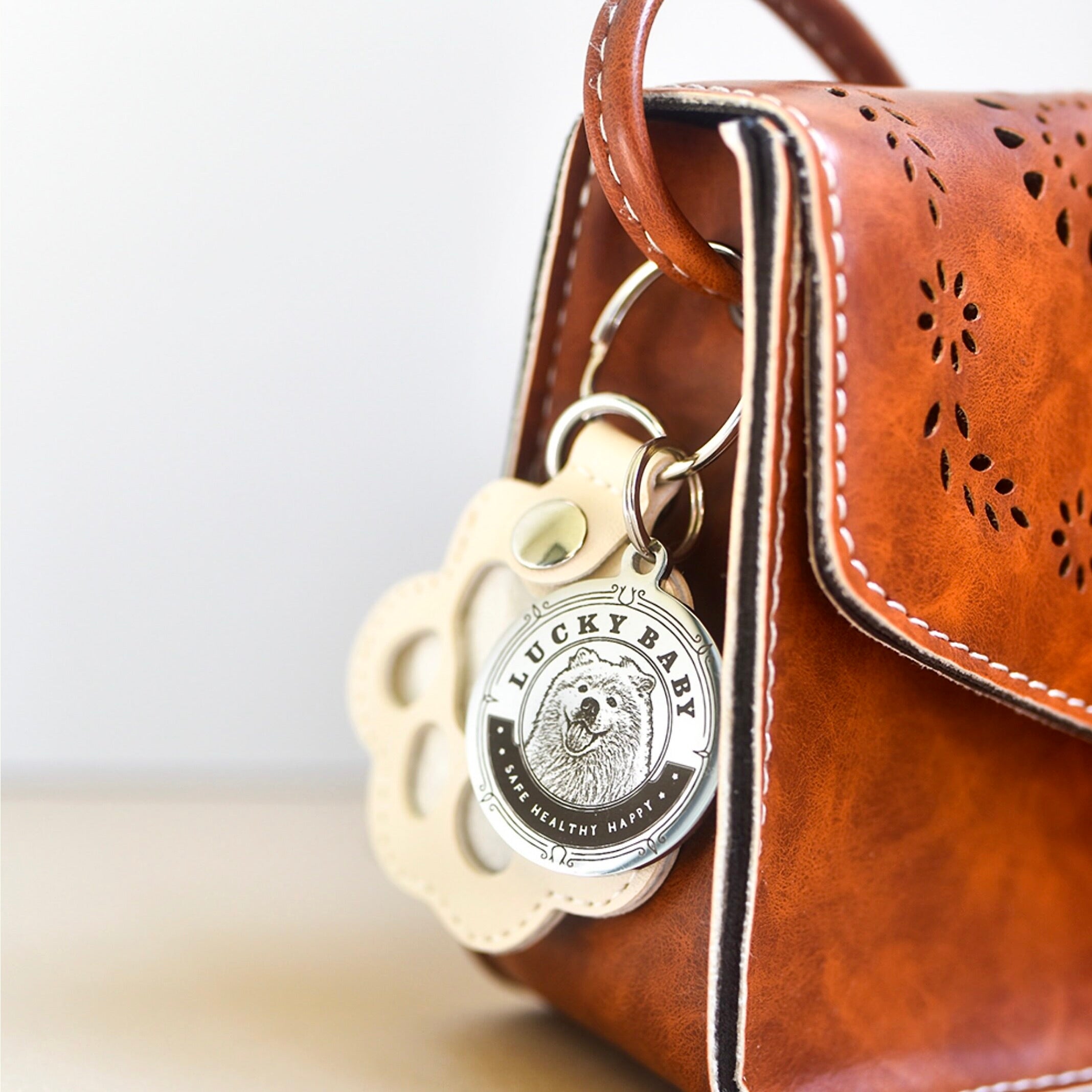 Brown leather bag with a 'Lucky Baby' keychain attached