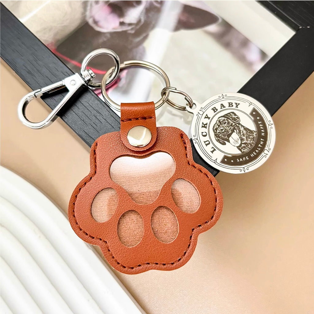 Brown leather paw-shaped keychain with a silver tag on a book