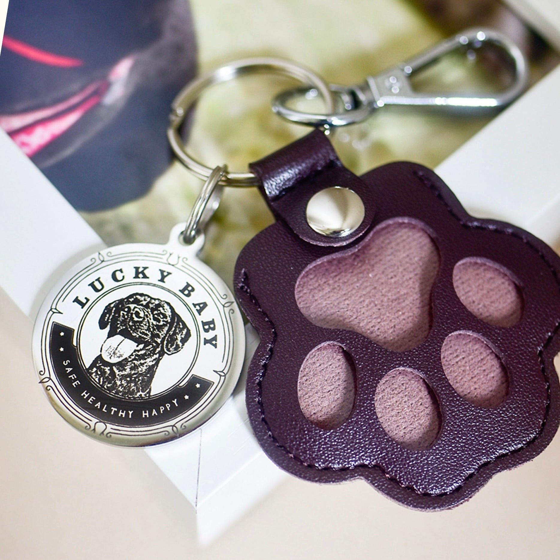 Keychain with 'Lucky Baby' tag and paw-shaped leather tag on a white surface.