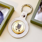 Round lucky coin keychain with white leather strap on a light surface