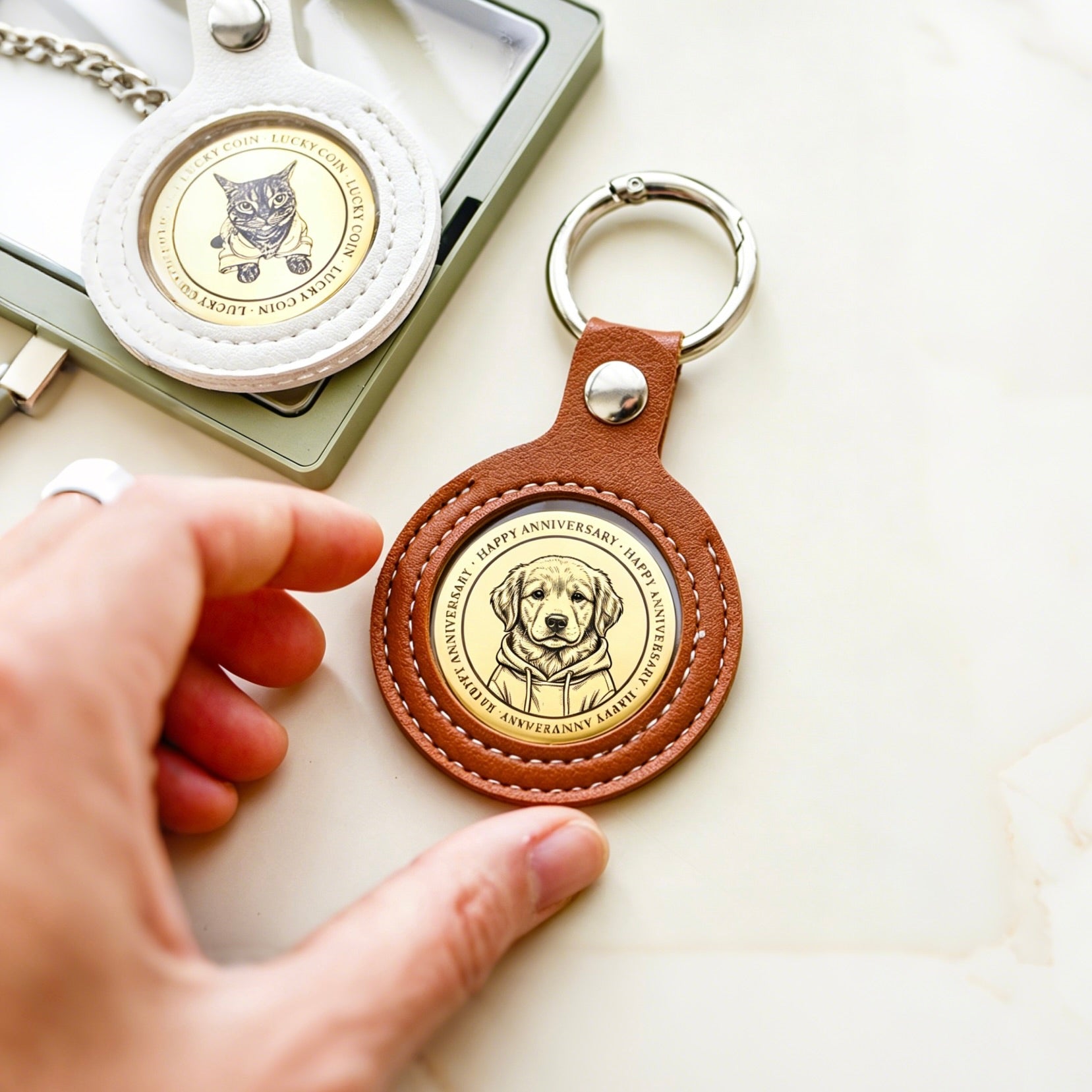 Brown leather keychain with engraved dog design held by a hand on a light surface.