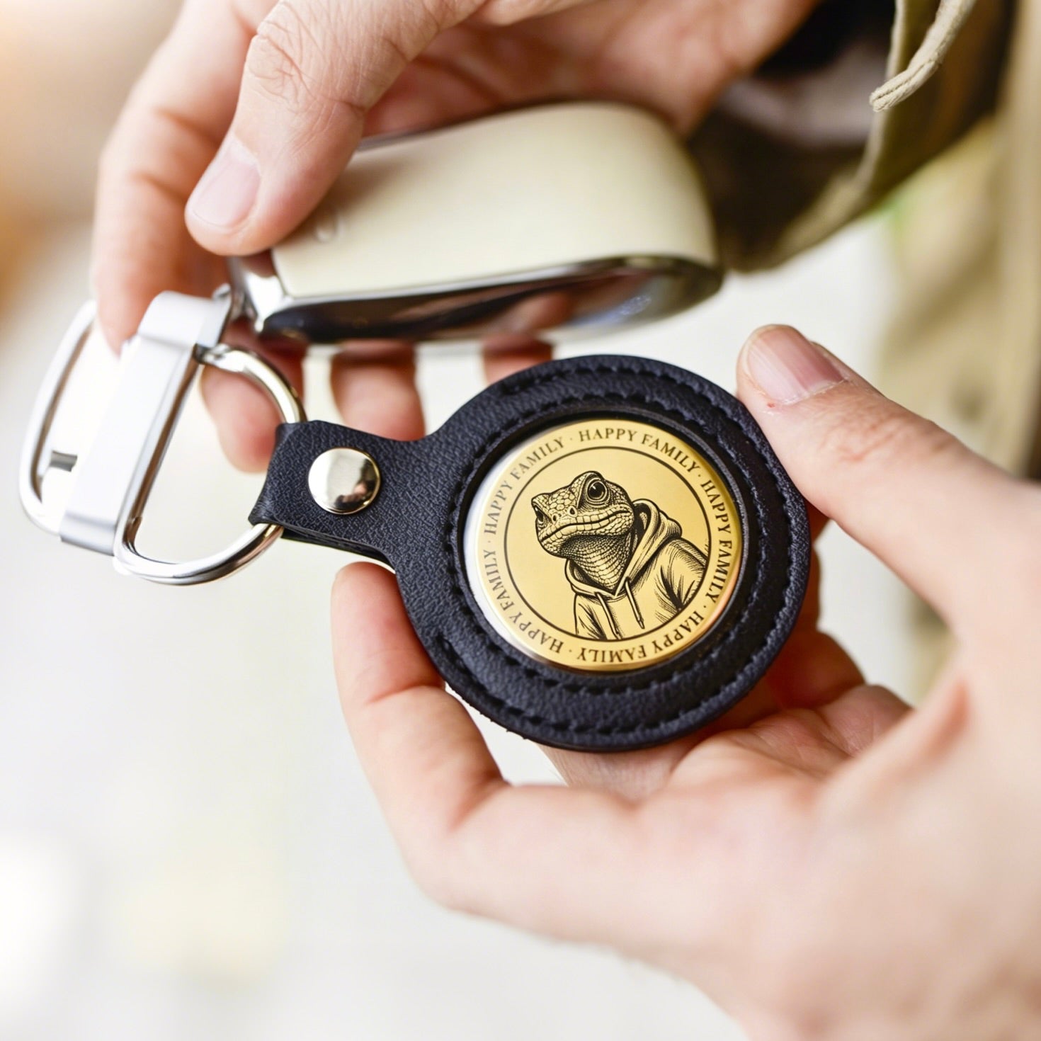 Person holding a keychain with a circular emblem featuring a frog illustration.
