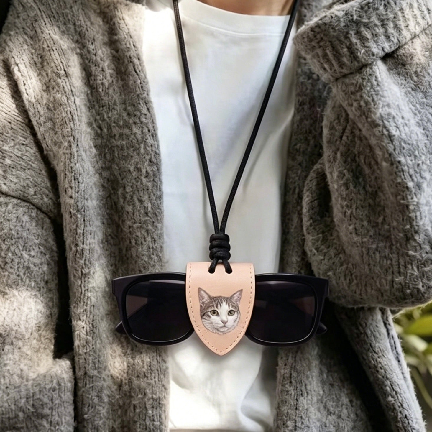 Person wearing a necklace with sunglasses featuring a cat design