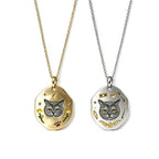 Two cat-themed necklaces, one gold and one silver, on a white background.