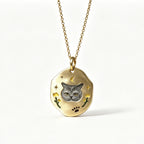 Gold necklace with a pendant featuring a cat's face on a white background