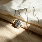 Silver necklace with a cat pendant on a beige fabric background