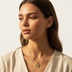 Woman wearing a gold necklace with a pendant against a neutral background