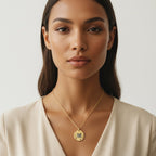Woman wearing a gold necklace with a pendant against a neutral background