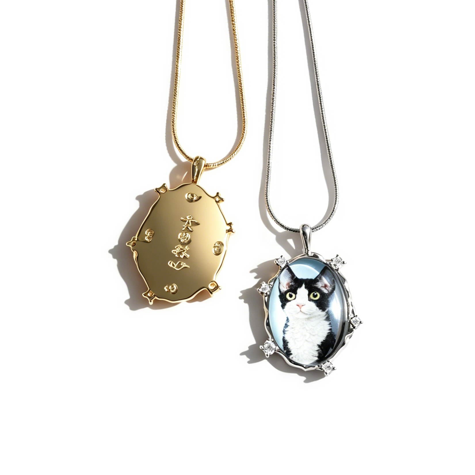 Two necklaces with pendants, one gold and one with a cat design, on a white background.