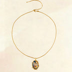 Gold necklace with a pendant on a beige background