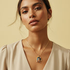 Woman wearing a gold necklace with a pendant against a beige background