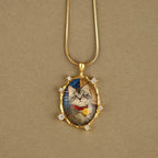 Gold necklace with a pendant featuring a cat's face on a beige background