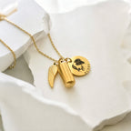Gold necklace with charms on a white dish