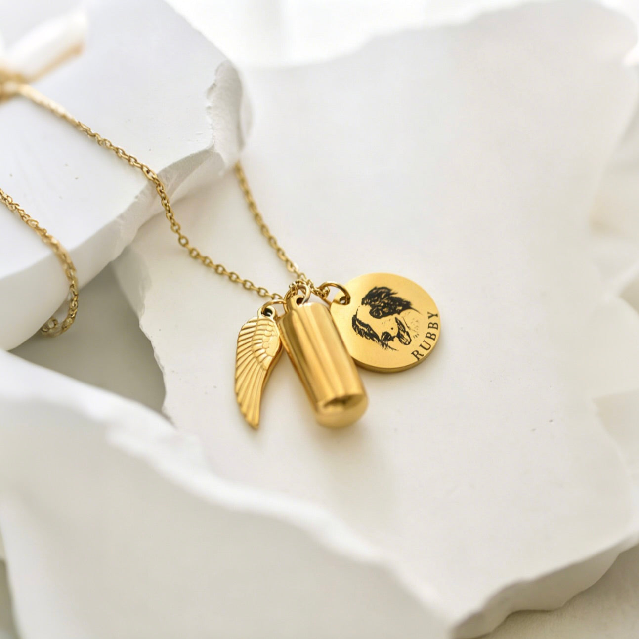 Gold necklace with charms on a white dish