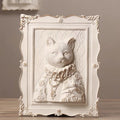 Decorative wall art of a cat with ornate frame on a wooden surface.