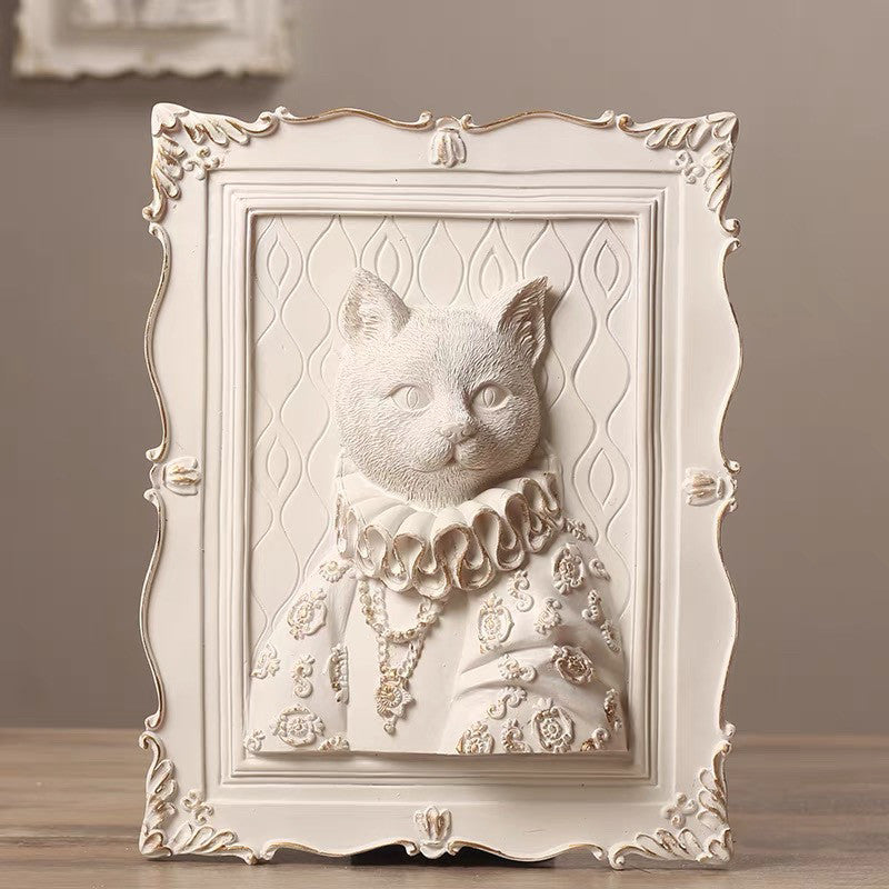 Decorative wall art of a cat with ornate frame on a wooden surface.