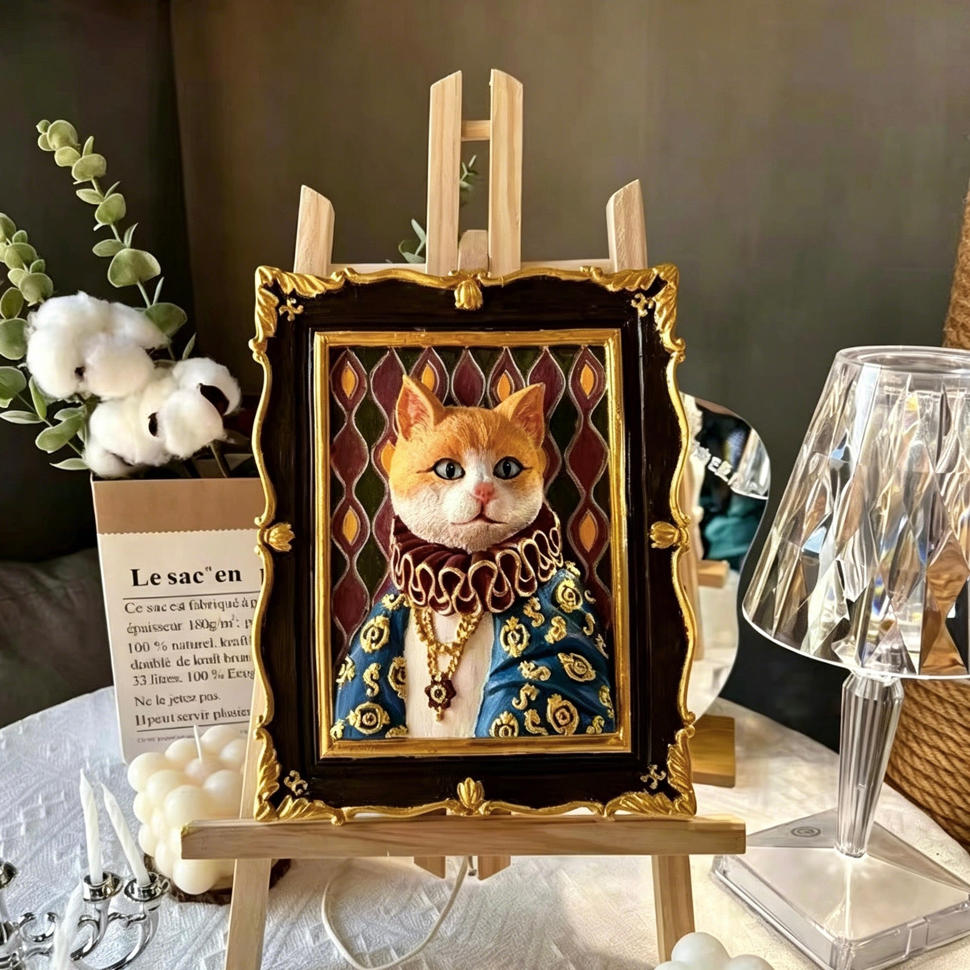 Decorative painting of a cat in regal attire on an easel with a blurred background