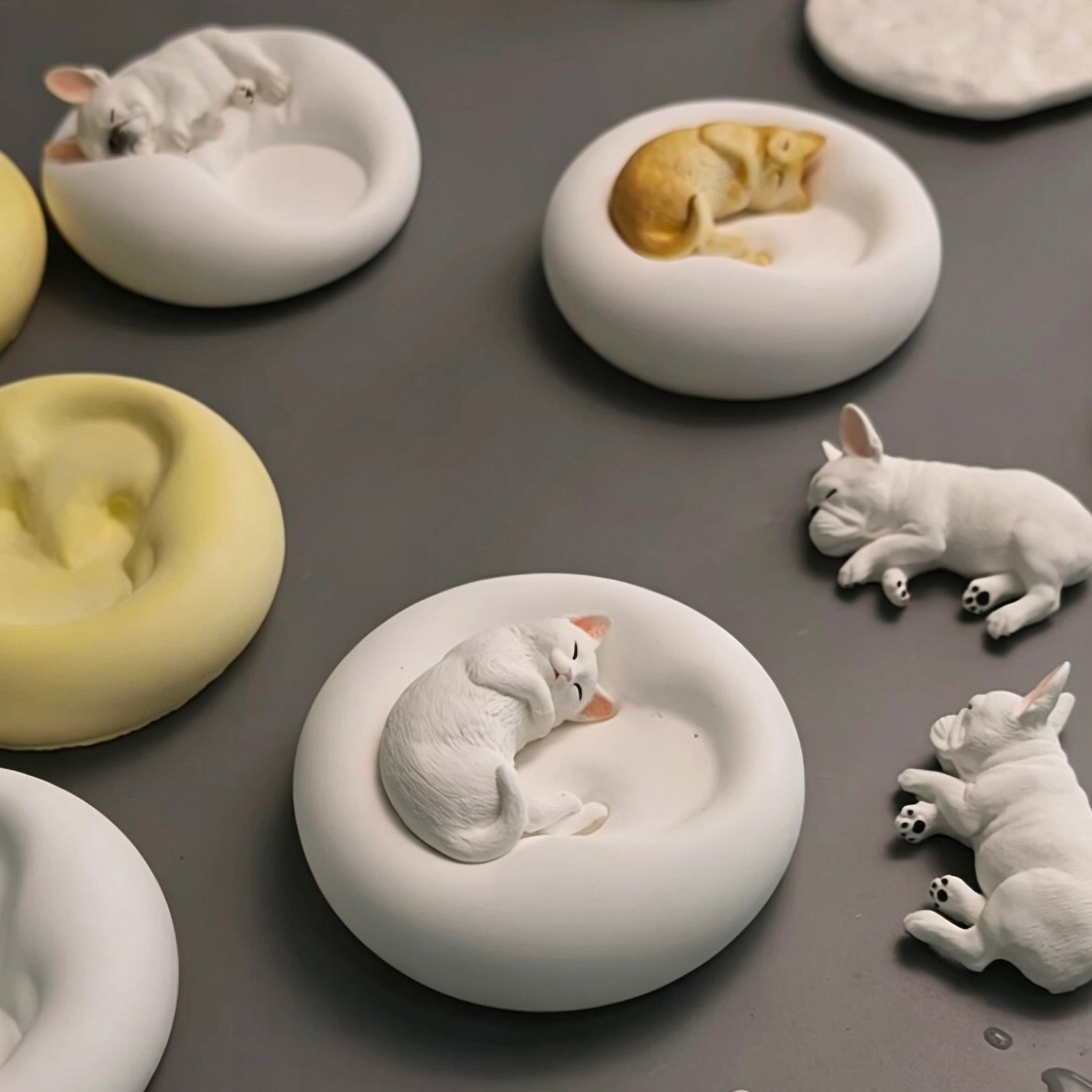 Collection of plaster pet candle holders and jewelry trays featuring sleeping French Bulldog and cat designs