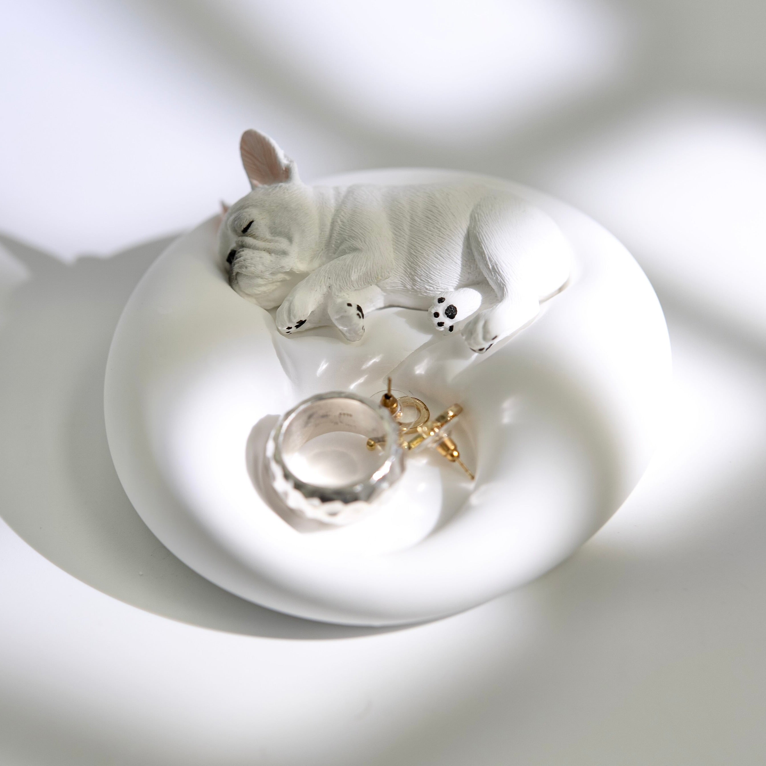 Matte white plaster sleeping French Bulldog jewelry tray and candle holder displaying a ring and earrings