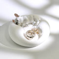 Matte white plaster sleeping French Bulldog jewelry tray and candle holder displaying a ring and earrings