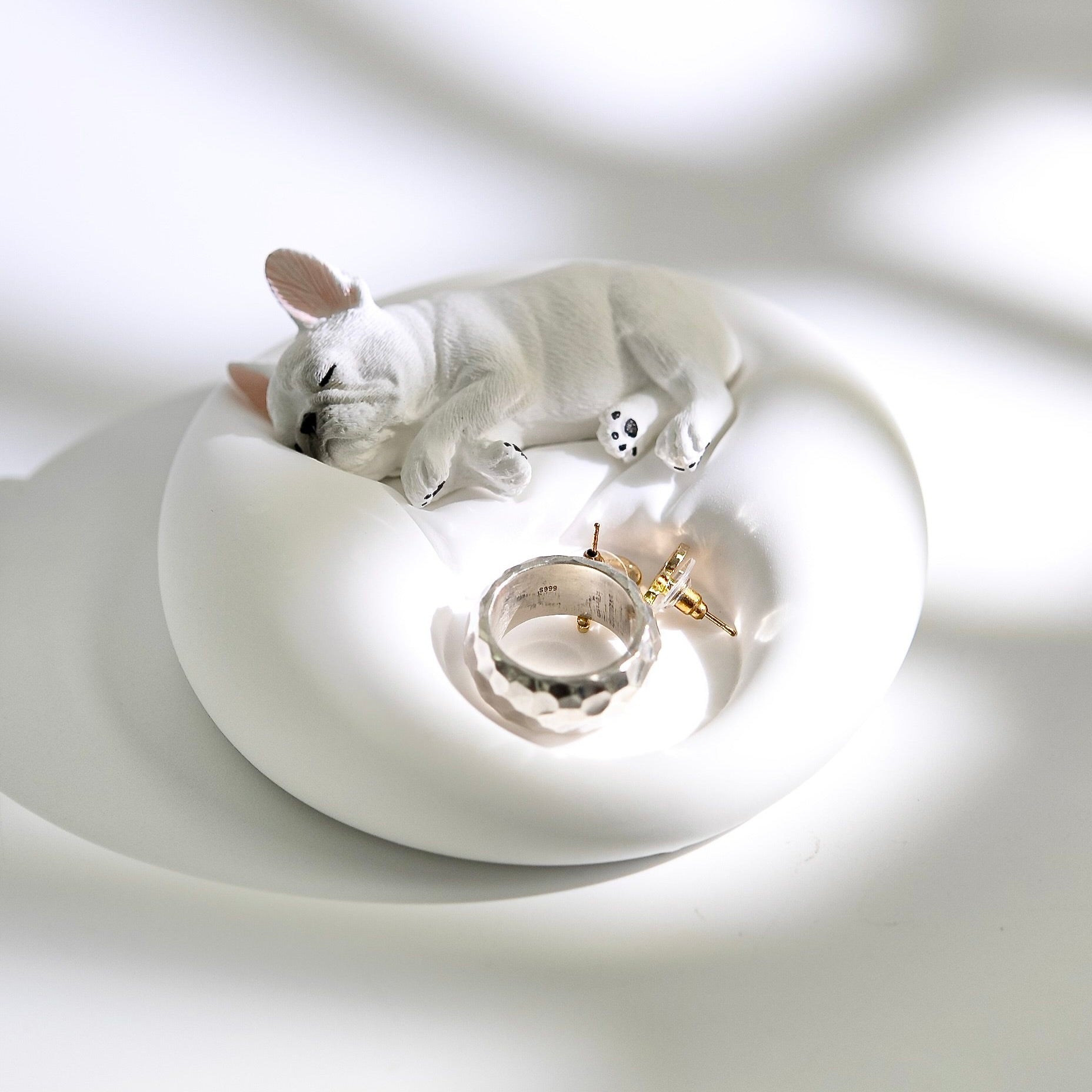 Matte white plaster sleeping French Bulldog jewelry tray and candle holder displaying a ring and earrings