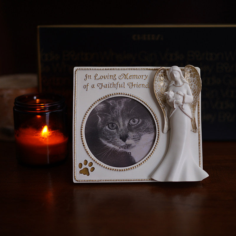 Memorial photo frame with angel sculpture and cat photo, candle in the background