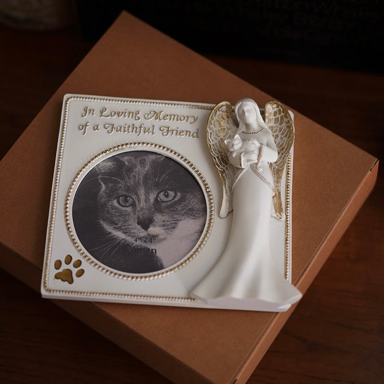 Memorial plaque with a cat's photo and angel figurine on a brown surface