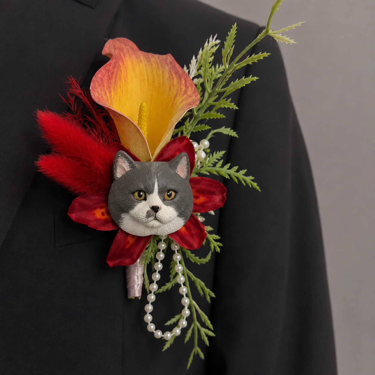 Hand-painted plaster tuxedo cat wedding boutonniere lapel pin with an orange calla lily, red accents, and hanging pearls.