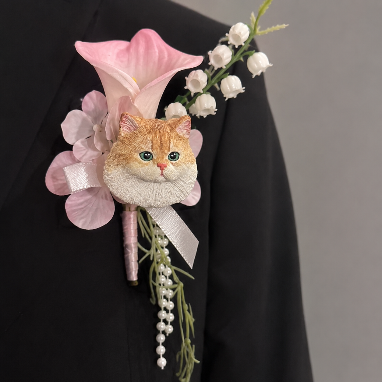 Hand-painted plaster orange tabby cat wedding boutonniere lapel pin with a pink calla lily, lily of the valley, and dangling pearls.