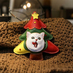 Christmas tree-shaped keychain with a cat face on a textured surface