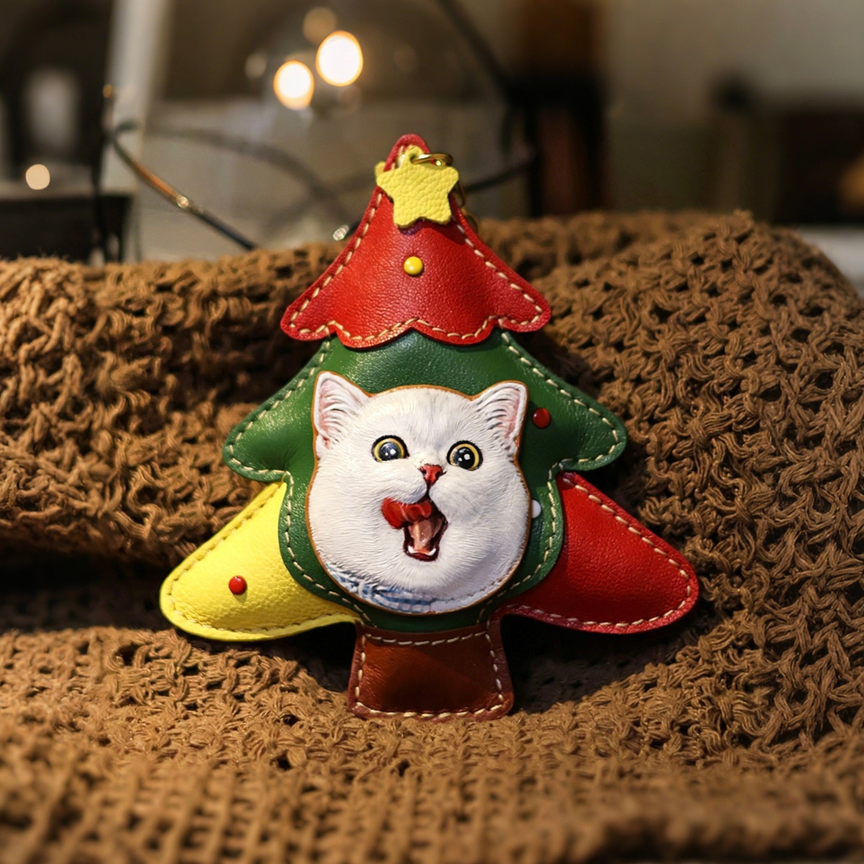 Christmas tree-shaped keychain with a cat face on a textured surface