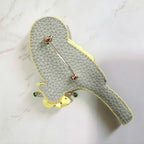 Gray textured clutch with gold and green accents on a light gray background