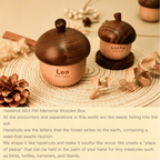Wooden pet memorial box shaped like an acorn with 'Leo' and 'Lucky' inscriptions, surrounded by dried flowers and pinecones.