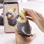 Person holding a small bird-like plush toy next to a smartphone displaying an image of a similar bird.