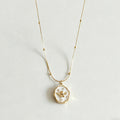 Gold necklace with a pendant on a light gray background