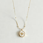 Gold necklace with a pendant on a light gray background