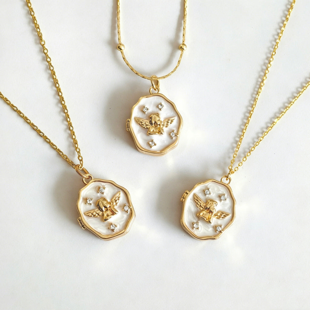 Three gold necklaces with angel pendants on a white background
