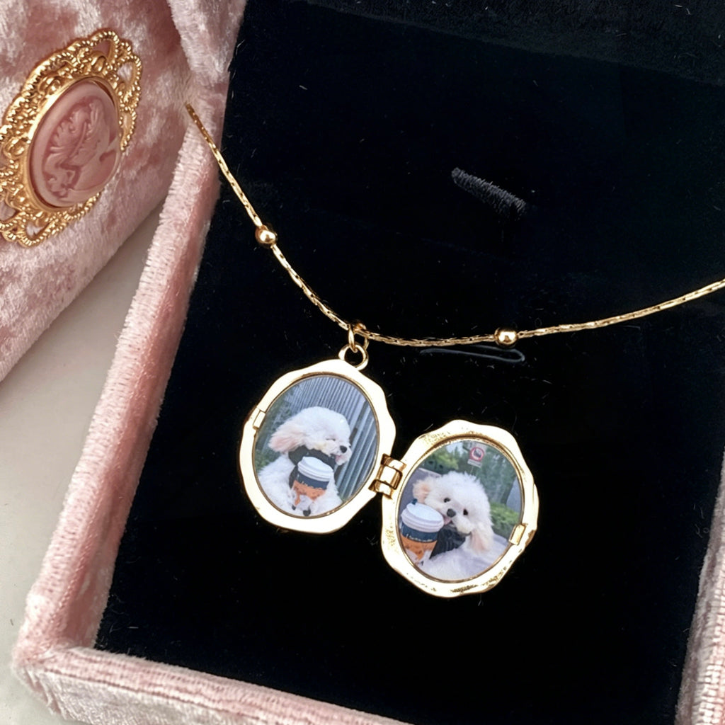 Gold necklace with locket pendant featuring images of a dog on a black velvet surface.