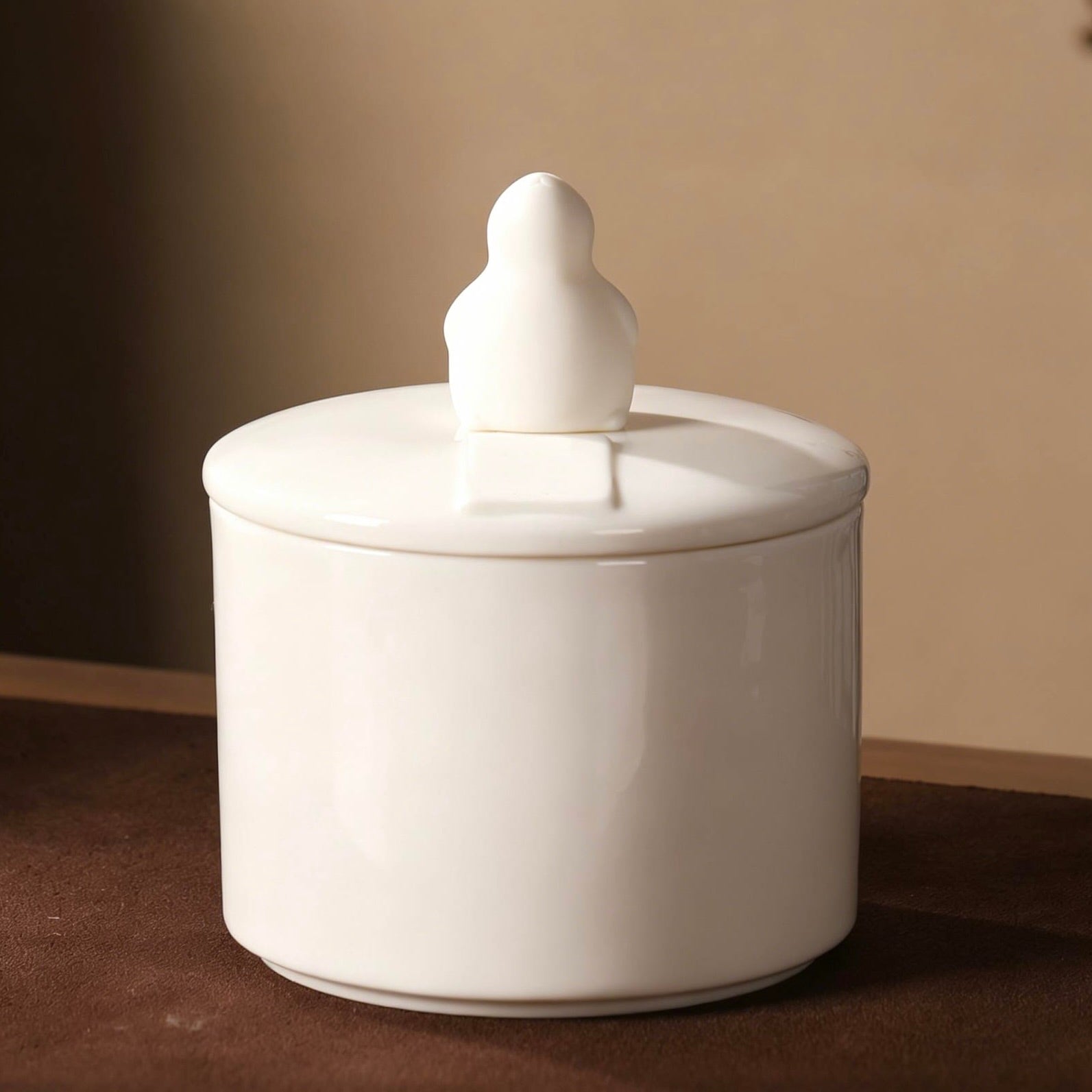 White ceramic jar with a lid and decorative figure on a brown surface