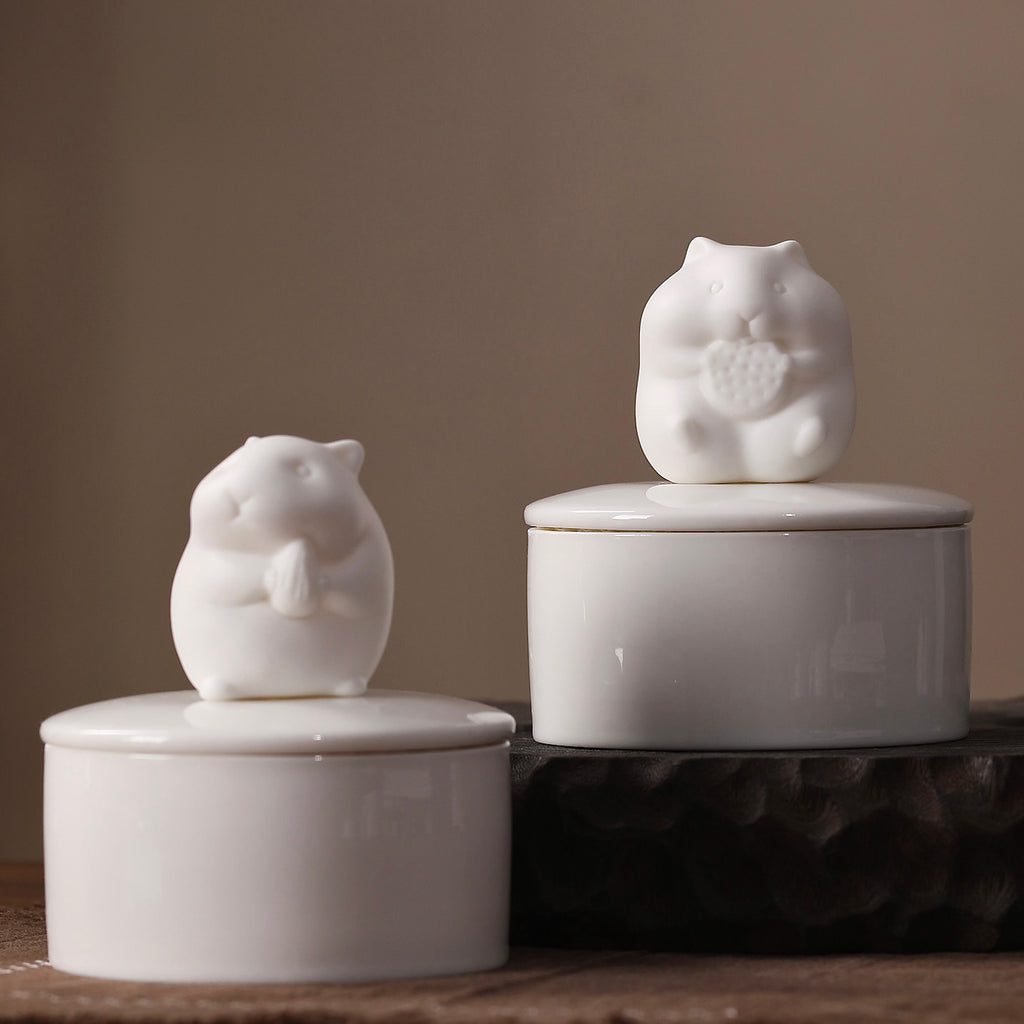White ceramic jar with a bird-shaped lid on a wooden surface.
