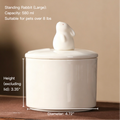 Person holding a white ceramic tea infuser with a lid on a wooden 