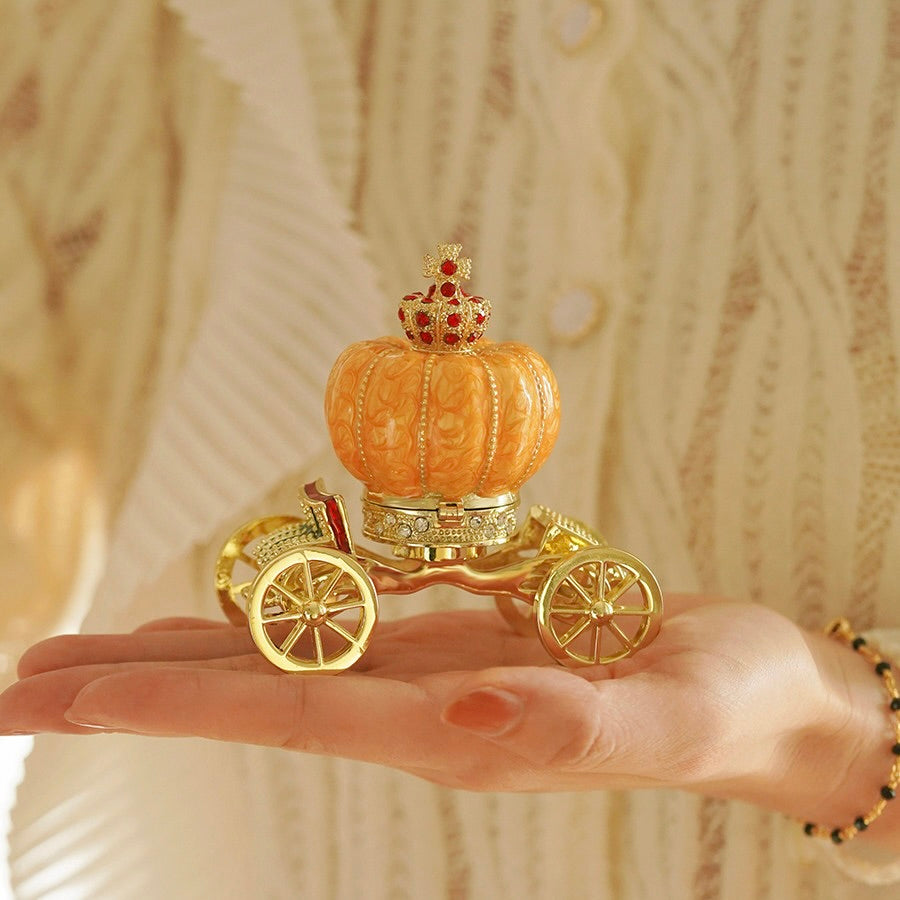 Decorative pumpkin with a gold carriage on a hand against a neutral background